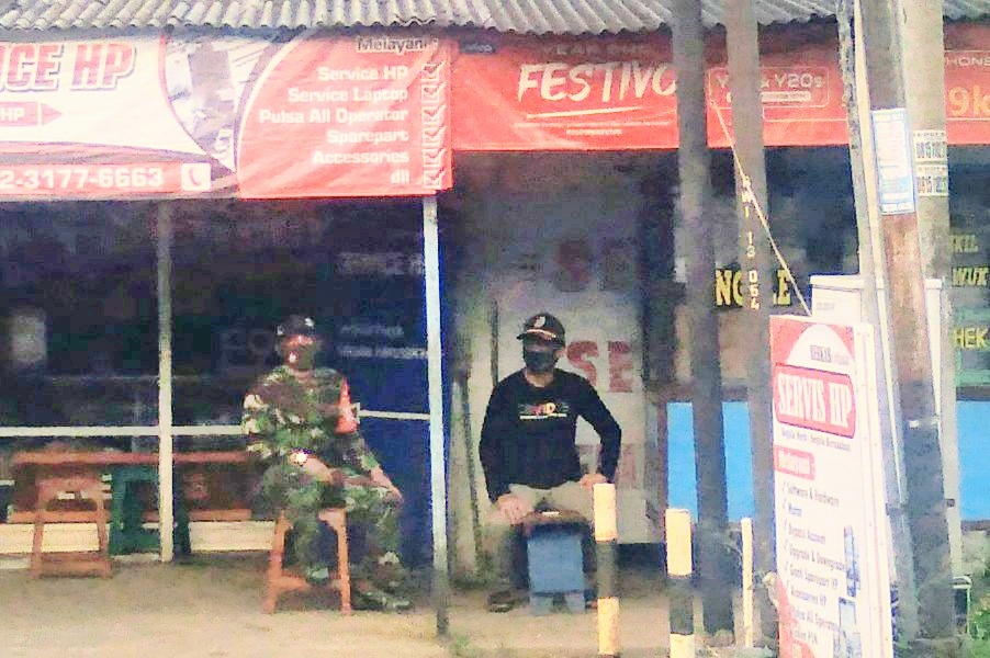 Babinsa dan perangkat Desa Cluring tampak mengamankan kegiatan bagi-bagi takjil yang mengundang kerumunan