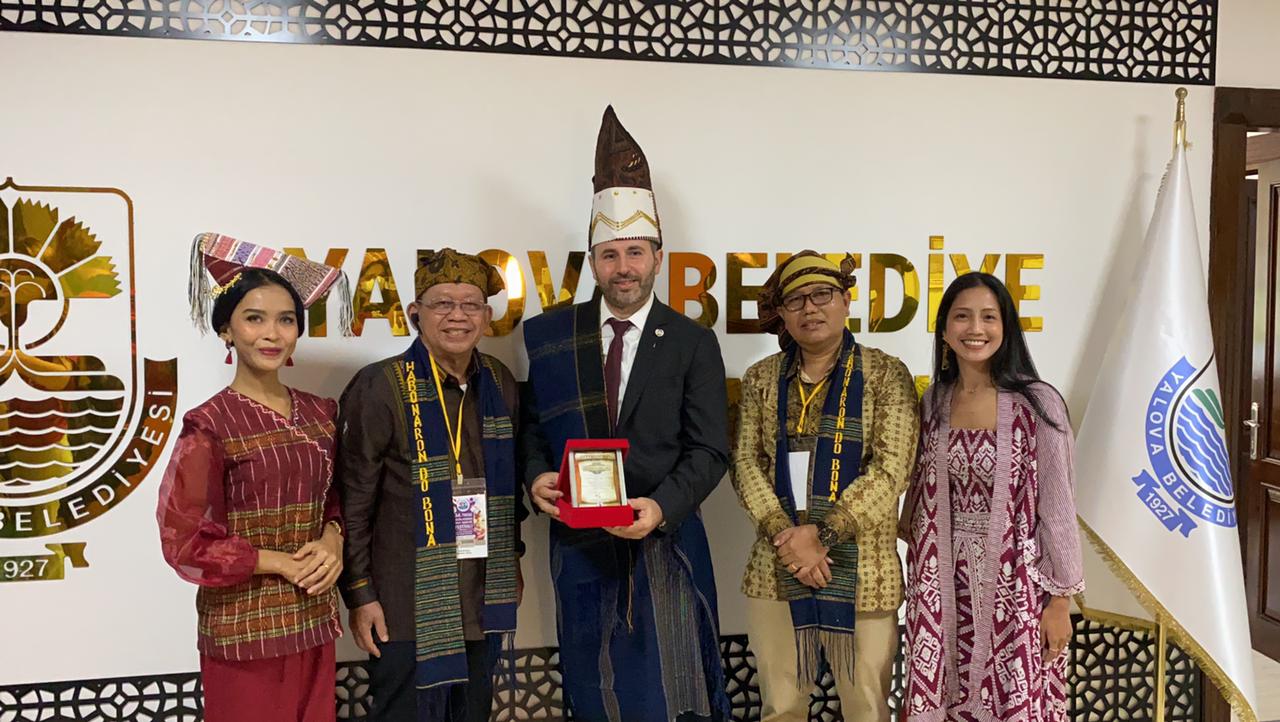 Ketua DPP PMS Sarmedi Purba, Bendahara PB7KS Jabetson Purba Sigumonrong, pimpinan SIHODA Laura Sinaga dan perwakilan CIOFF Indonesia Nurmala Dewi Sari saat Pemberian cinderamata berupa pakaian adat Simalungun kepada Walikota Yalova Turki, Mr. Mustafa Tutuk.