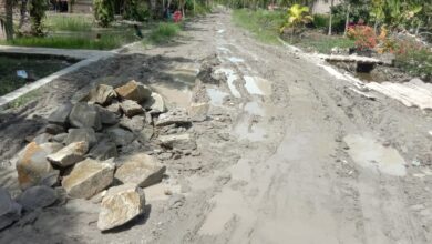 Kondisi akses jalan Desa Kapal Merah dan matrial bangunan bangunan menutupi jalan yang rusak.